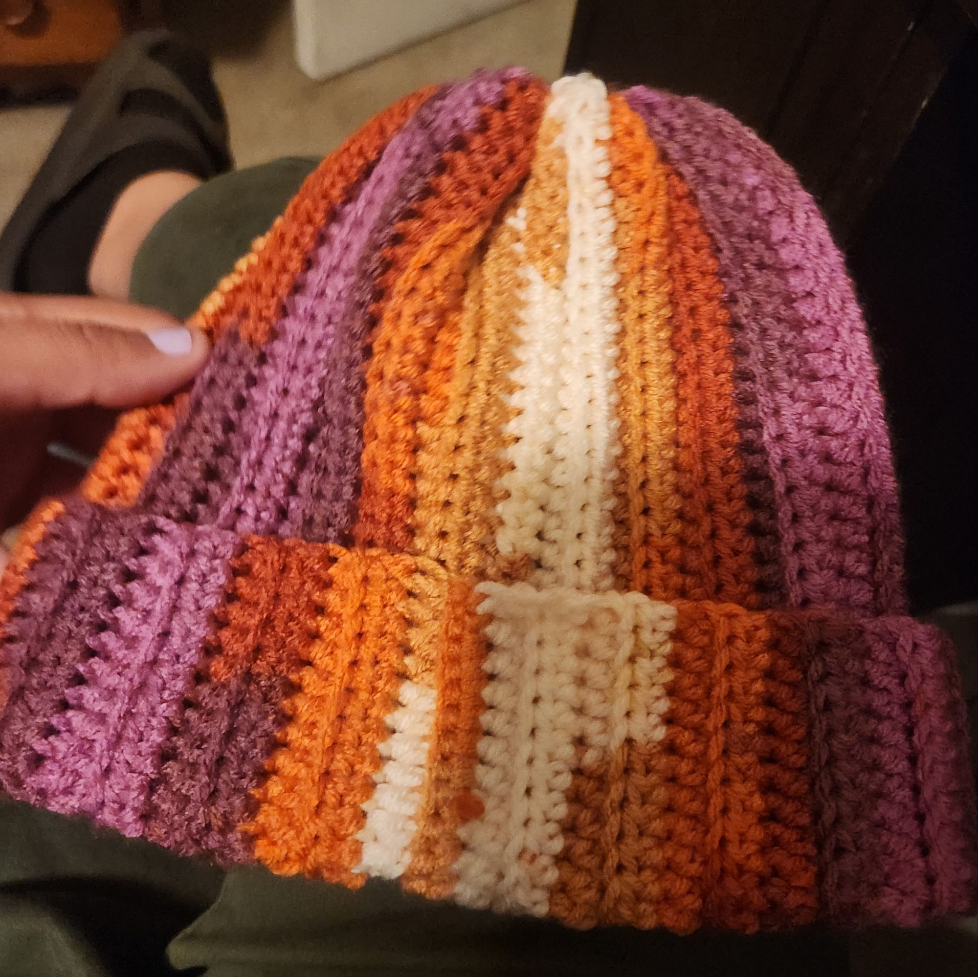 A crochet beanie made with the colors of the lesbian flag.